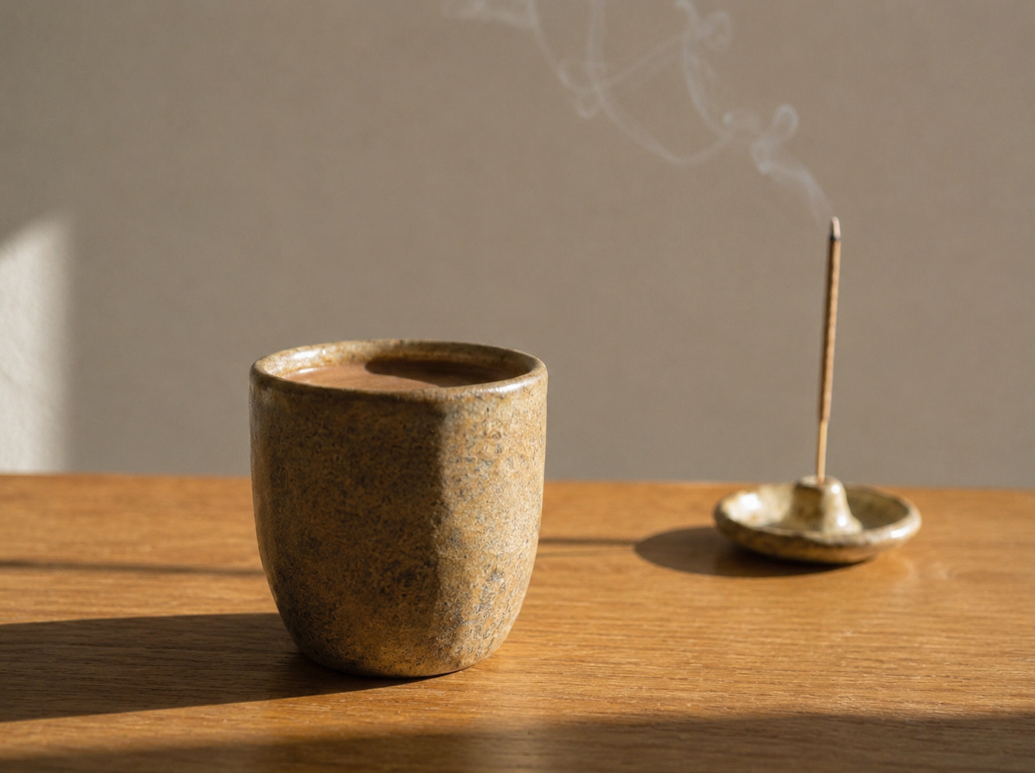 A warm cup of stone-ground drinking chocolate with an incense holder and stick
